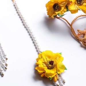 May include: A set of yellow flower hair accessories with pearl strands. The set includes a headband and a hair clip.