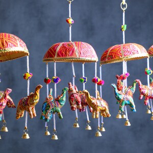 May include: A colorful mobile with red, gold, and white fabric umbrellas and hanging elephant ornaments. The elephants are decorated with colorful embroidery and beads.