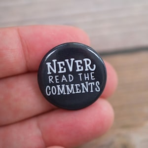 May include: A black button with white text that reads "NEVER READ THE COMMENTS".