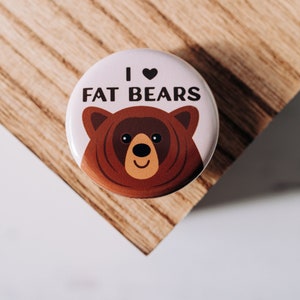 May include: A white button with a brown bear illustration and the text "I ♥ FAT BEARS".