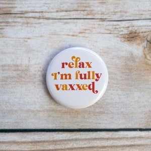May include: A white button with the text "relax I'm fully vaxxed" in orange and red lettering.