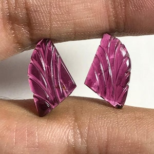 May include: A pair of carved pink gemstone earrings with a fan-shaped design.