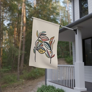 Könnte beinhalten: Eine beige Gartenflagge mit einem stilisierten Blumendesign. Die Blumen sind in den Farben Rosa, Gelb, Blau und Grün gehalten. Die Worte "Akzeptanz rettet Leben" stehen auf den Blumen.