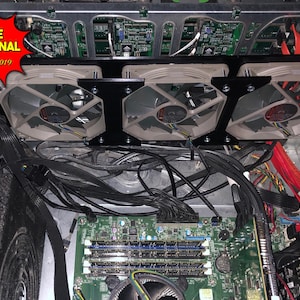 May include: Close-up of a computer's internal components, including a motherboard with RAM slots, a power supply unit, and multiple fans. The fans are black with beige blades and are mounted on a black metal frame. The motherboard is green and has several chips and connectors.