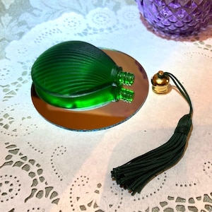 Flat, shell-shaped perfume bottle in smooth satin-glass. Ribbed top, smooth back; refillable. Pure solid green with gold cap.  3 x 2 inches