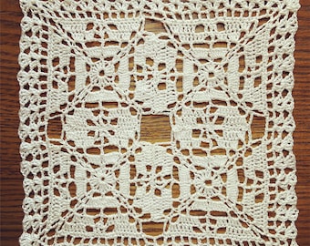 May include: A white crocheted doily with a square design. The doily has a delicate, intricate pattern and is made with fine yarn.
