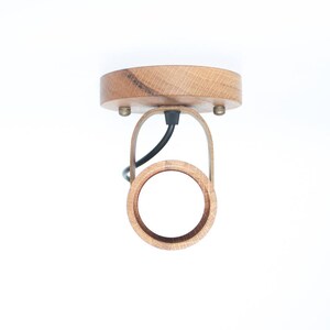 May include: A wooden ceiling light fixture with a circular shade and a black wire.