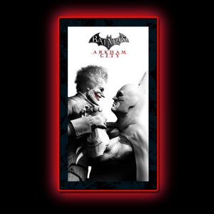 以下が含まれることがあります： バットマンとジョーカーが向き合っている白黒の画像。画像の上部には「BATMAN ARKHAM CITY」の文字があります。