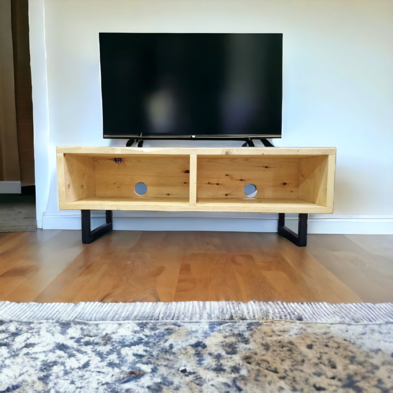 May include: A wooden TV stand with two shelves and black metal legs. The stand is made of reclaimed wood and has a rustic look.