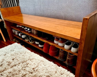Könnte beinhalten: Ein Schuhregal aus Holz mit zwei Ablagen, gefüllt mit verschiedenen Schuhen, darunter Sneakers, Sandalen und Stiefel. Das Regal ist aus hellem Holz gefertigt und hat eine natürliche Oberfläche.