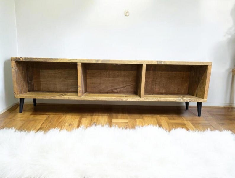 May include: A rustic wooden shelf unit with three open compartments. The shelf has a natural wood finish and black metal legs.