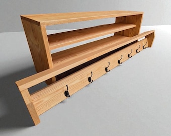 Könnte beinhalten: Ein hölzernes Eingangsspeichergerät mit einem Regal und einem unteren Abschnitt mit sechs schwarzen Haken. Das Gerät besteht aus hellfarbenem Holz und hat ein modernes Design. Das Regal ist etwa 122 cm breit.