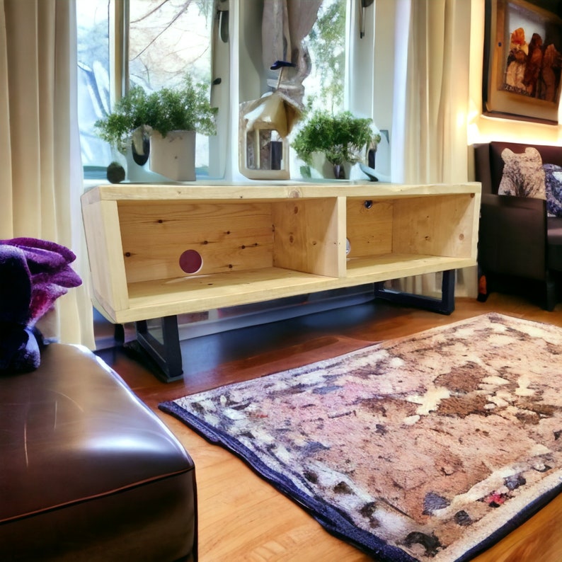 May include: A light wood entertainment center with two open shelves and black metal legs. The center is sitting on a wood floor with a patterned rug in front of it.