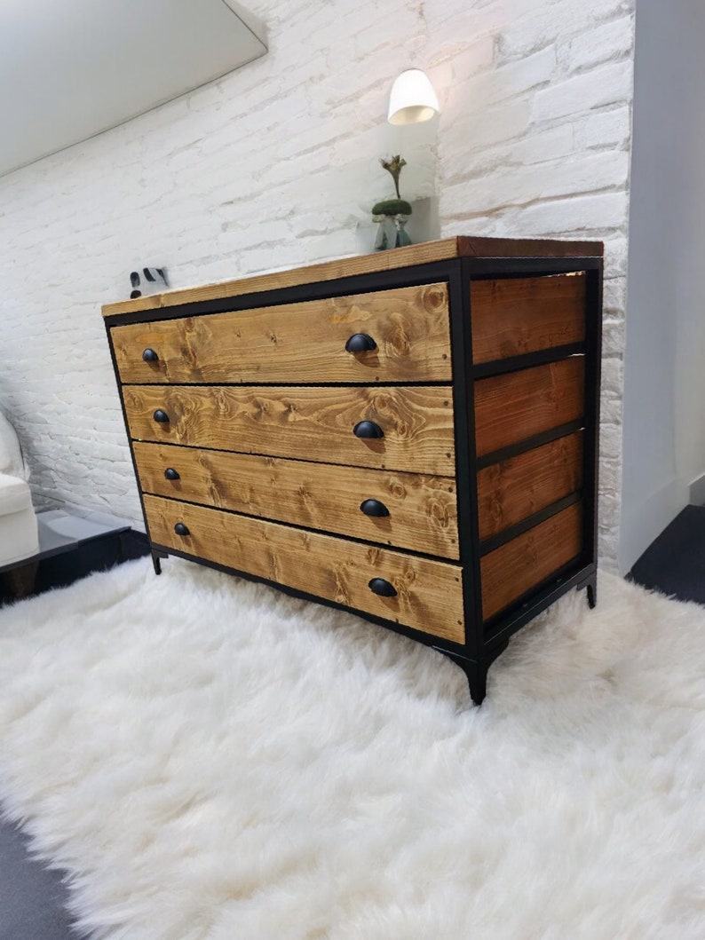 May include: A four-drawer dresser with a black metal frame and wooden drawers. The dresser has a rustic, industrial style and is sitting on a white fluffy rug.