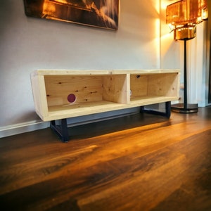 May include: A wooden entertainment center with two shelves and black metal legs. The unit is made of light wood and has a natural finish.