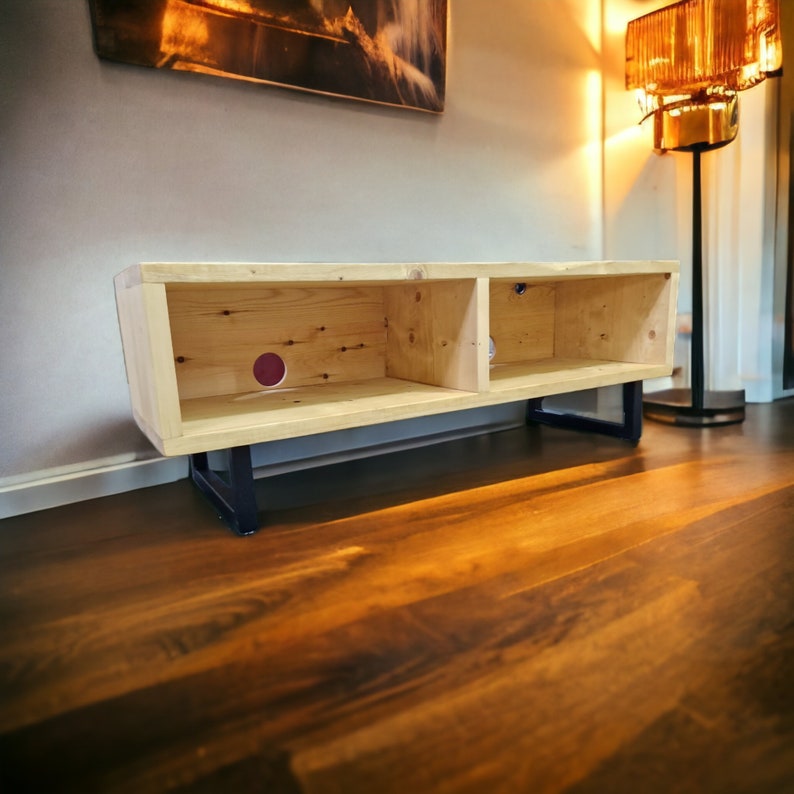 May include: A wooden entertainment center with two shelves and black metal legs. The unit is made of light wood and has a natural finish.