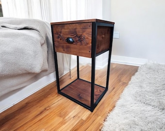 May include: A wooden nightstand with a black metal frame. The nightstand has one drawer and a lower shelf. The drawer has a black metal knob.
