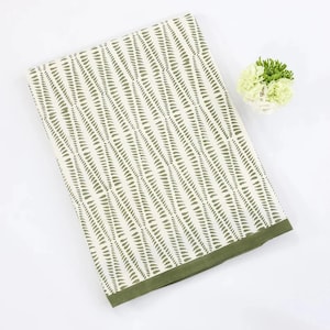 May include: A white tablecloth with a green leaf pattern. The tablecloth has a green border and is folded in half.
