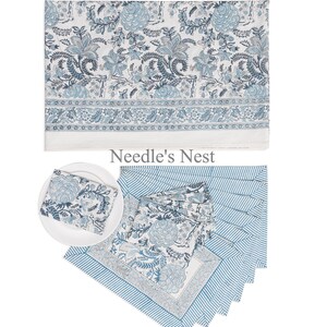 May include: A collection of blue and white floral patterned table linens. The set includes a tablecloth, napkins, and placemats. The tablecloth features a large floral design, while the napkins and placemats have a smaller floral pattern and striped borders. The brand name "Needle's Nest" is visible.