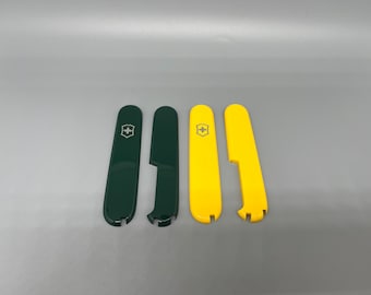 May include: Two pairs of replacement scales for a multi-tool pocket knife. One pair is dark green and the other is bright yellow. Each set includes a front scale with a silver Swiss cross emblem and a back scale with a cutout for tools.