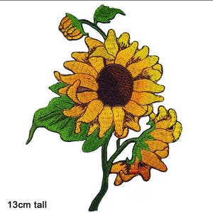 May include: Embroidered sunflower patch, 13cm tall, featuring a large yellow flower with a dark brown centre, green leaves, and a stem. The patch includes a bud and a smaller flower. The text "13cm tall" is at the bottom.
