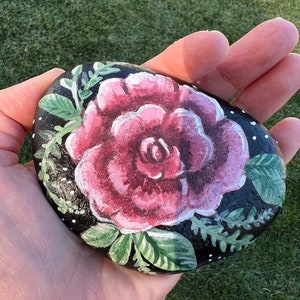 Hand painted rose on a flat river rock.