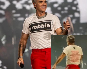ROBBIE: Camiseta de doble cara usada por Robbie Williams, fechas de la gira europea 2026. Tallas de la S a la 4XL. Tejido orgánico de primera calidad.