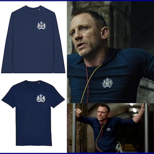 Può includere: Maglietta e maglia a maniche lunghe blu navy con un emblema bianco a forma di stemma sul petto. L'immagine mostra anche una persona che indossa una maglietta simile. Le magliette sono realizzate in un materiale morbido e confortevole.