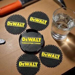 May include: A collection of black coasters with a saw blade design and the yellow "DEWALT" logo. One coaster has the text "GUARANTEED TOUGH". A glass of water and a hammer are also visible on the wooden surface.