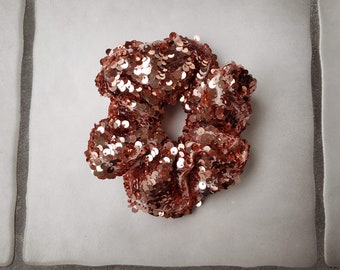 May include: A rose gold sequined hair scrunchie.