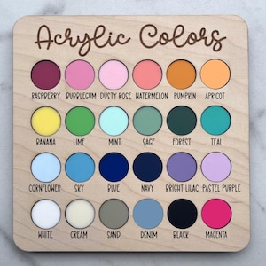 K&ouml;nnte beinhalten: Ein quadratisches Holzbrett mit der Aufschrift Acrylic Colors und vierundzwanzig kreisf&ouml;rmigen Ausstanzungen, die mit verschiedenen Acrylfarbmustern gef&uuml;llt sind. Jeder Kreis ist mit dem entsprechenden Farbnamen beschriftet, darunter raspberry, bubblegum, dusty rose, watermelon, pumpkin, apricot, banana, lime, mint, sage, forest, teal, cornflower, sky, blue, navy, bright lilac, pastel purple, white, cream, sand, denim, black und magenta.