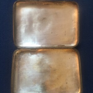 Op de afbeelding: Een zilveren sigarettenkoker met een scharnierend deksel. De koker heeft een versleten, verweerde uitstraling en is van binnen gemarkeerd met het nummer "800".