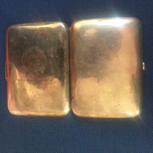 Op de afbeelding: Een zilveren sigarettenkoker met een gegraveerd ontwerp en de tekst "Sterling Silver" aan de voorkant.
