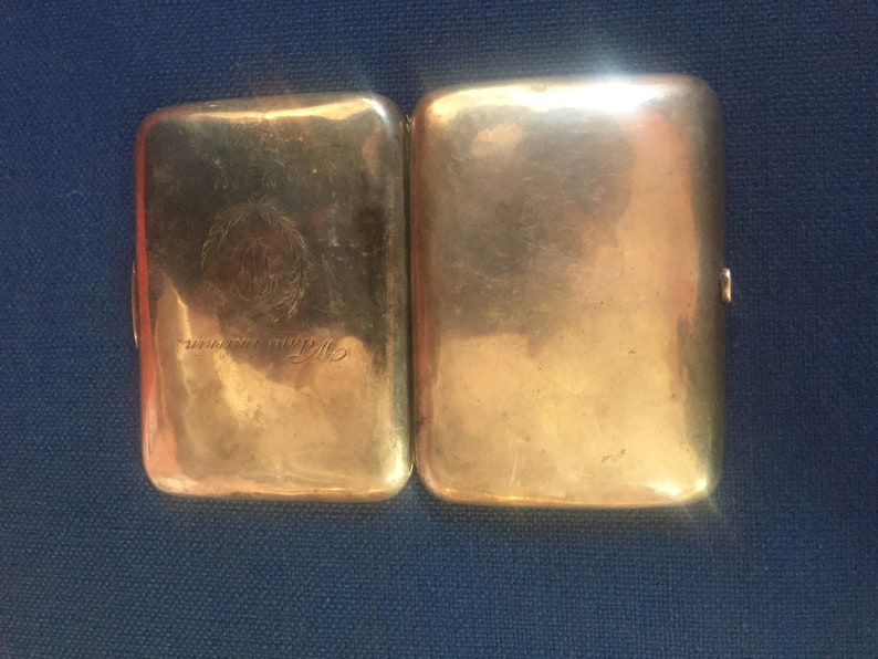 Op de afbeelding: Een zilveren sigarettenkoker met een gegraveerd ontwerp en de tekst "Sterling Silver" aan de voorkant.