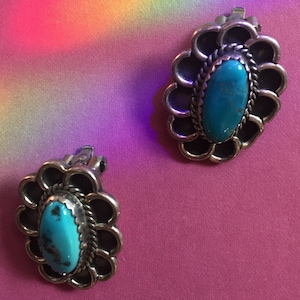 May include: A pair of silver earrings with turquoise stones set in a floral design.