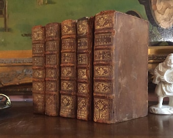 Op de afbeelding: Een set van zes antieke boeken met bruine lederen omslagen en gouden letters. De boeken zijn getiteld "The Theatre of Corneille" en zijn in een rij op een houten oppervlak gerangschikt.