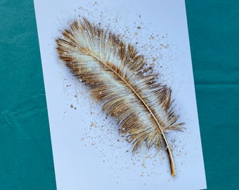 Puede incluir: Una pluma dorada sobre un fondo blanco con salpicaduras doradas de pintura.