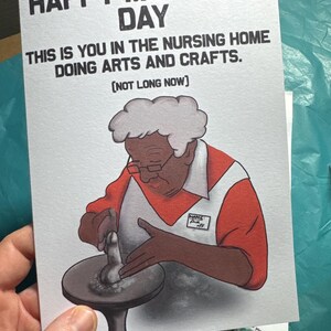 May include: A humorous greeting card with a cartoon illustration of a person in a nursing home doing arts and crafts. The card reads "Happy Mother's Day. This is you in the nursing home doing arts and crafts. [Not long now]"