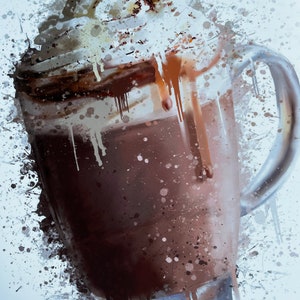 Puede incluir: Una taza de vidrio llena de una bebida de chocolate cubierta con crema batida y un chorrito de chocolate. La taza est&aacute; rodeada de salpicaduras de pintura blanca.