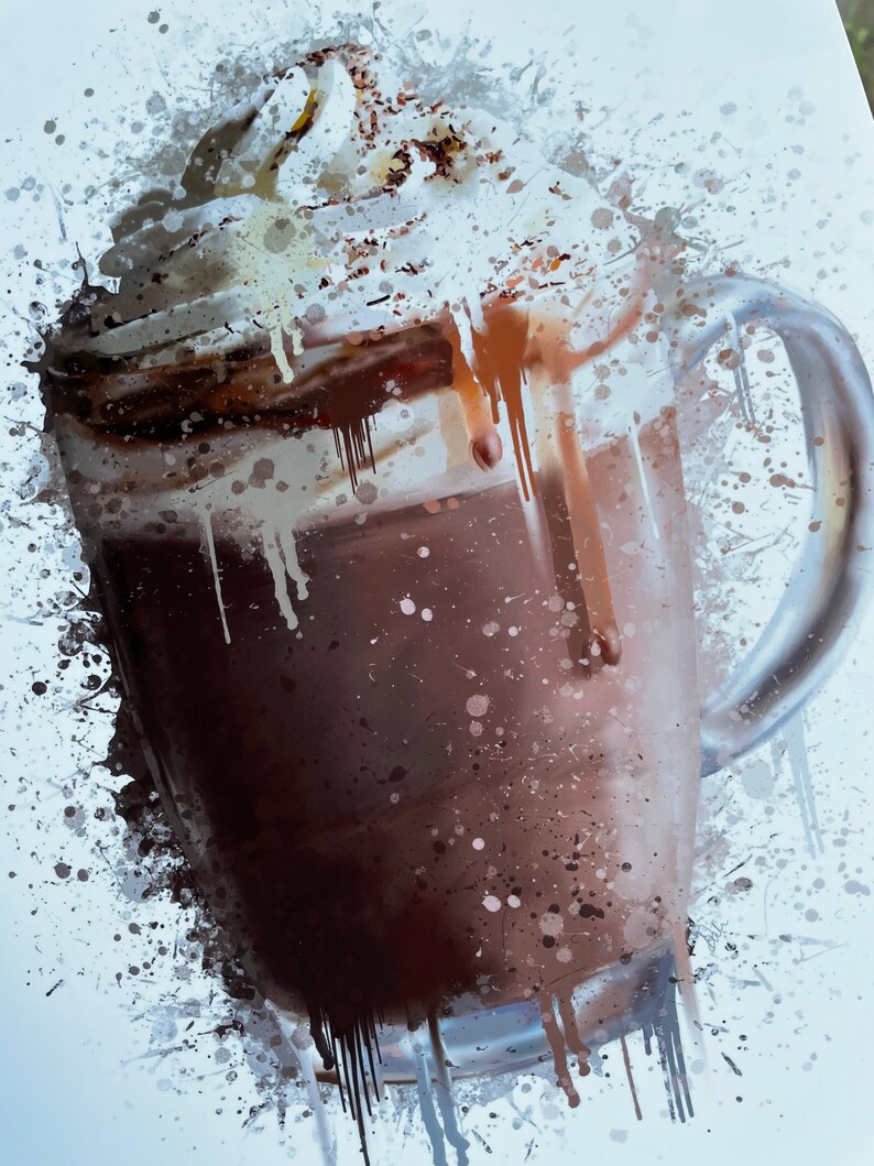 Puede incluir: Una taza de vidrio llena de una bebida de chocolate cubierta con crema batida y un chorrito de chocolate. La taza est&aacute; rodeada de salpicaduras de pintura blanca.