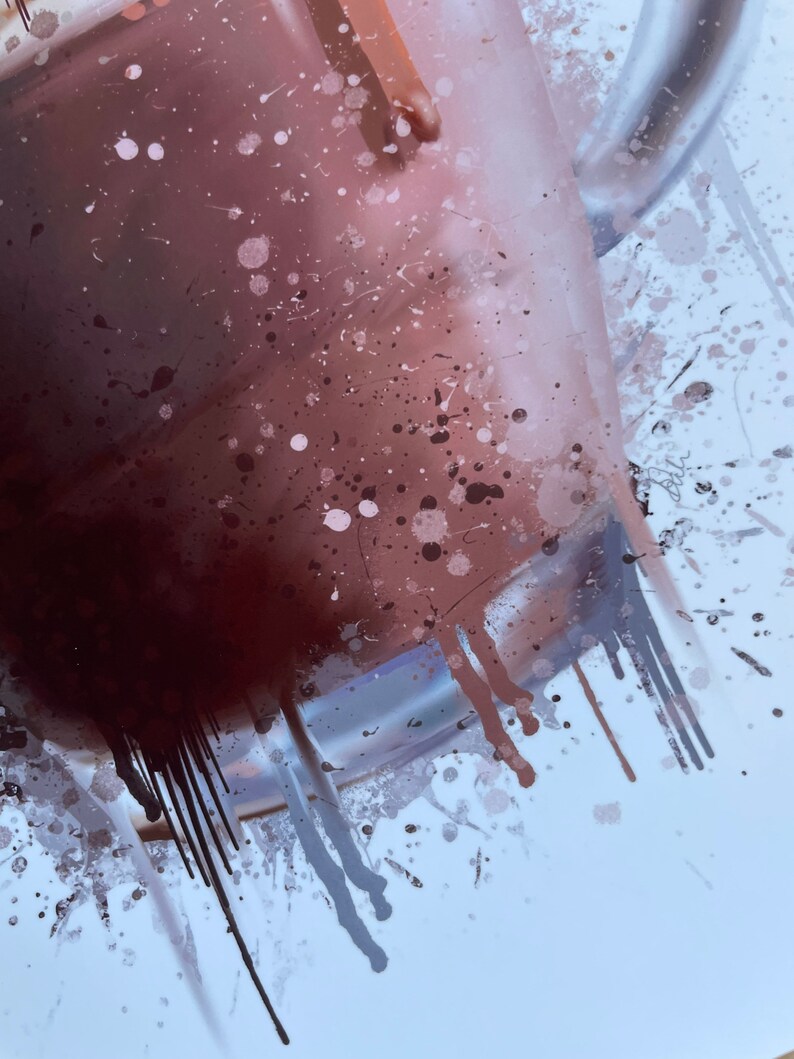 Puede incluir: Primer plano de una taza de vidrio llena de un l&iacute;quido marr&oacute;n oscuro, con salpicaduras de pintura marr&oacute;n y blanca sobre un fondo blanco.