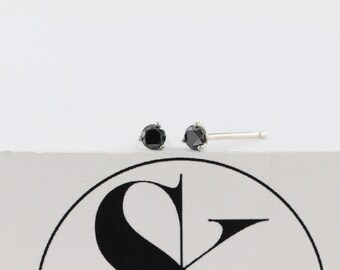 Könnte beinhalten: Ein Paar silberne Ohrstecker mit schwarzen Diamanten.