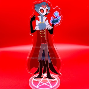 May include: An acrylic standee featuring a tall, slender character with grey feathers, red eyes, and a white collar with black markings. The figure wears a red jacket with gold buttons and a long cape, holding a glowing blue orb in one hand.