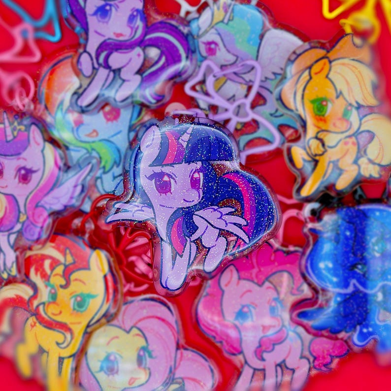May include: A collection of glittery acrylic charms featuring various cartoon ponies with colorful manes and tails. Each charm displays a unique character with large expressive eyes, set against a vibrant red background with scattered light reflections.