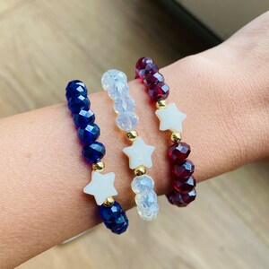 May include: Three beaded bracelets with star charms. The bracelets are blue, white and red.
