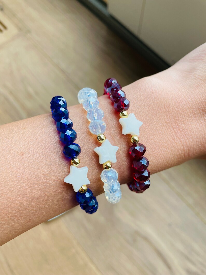 May include: Three beaded bracelets with star charms. The bracelets are blue, white and red.