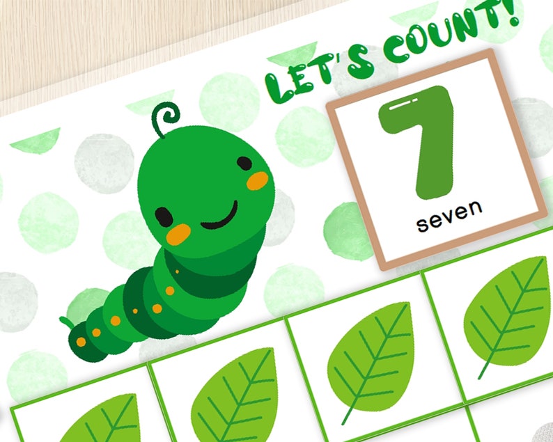 May include: A green caterpillar with a smiling face is on a white background with green polka dots. There are seven green leaves on the page. A brown card with the number 7 and the word "seven" is in the upper right corner. The text "Let's Count!" is in the upper right corner.