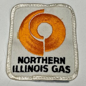 May include: A white embroidered patch with an orange circle logo and the text "NORTHERN ILLINOIS GAS" in black.