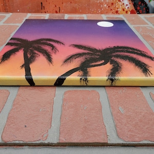 May include: A painting of two palm trees silhouetted against a sunset sky with a full moon. The sky is a gradient of orange, pink, and purple.