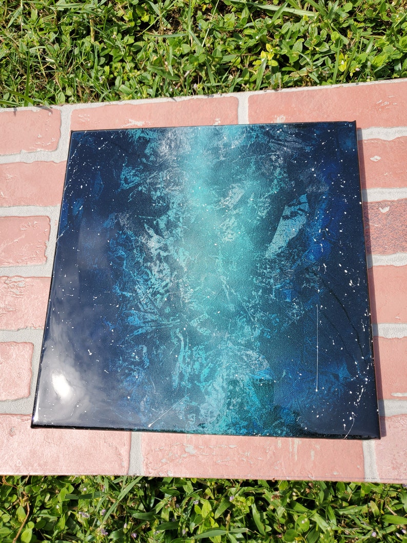 May include: A square canvas painting with a blue and green abstract design. The background is black with white speckles.